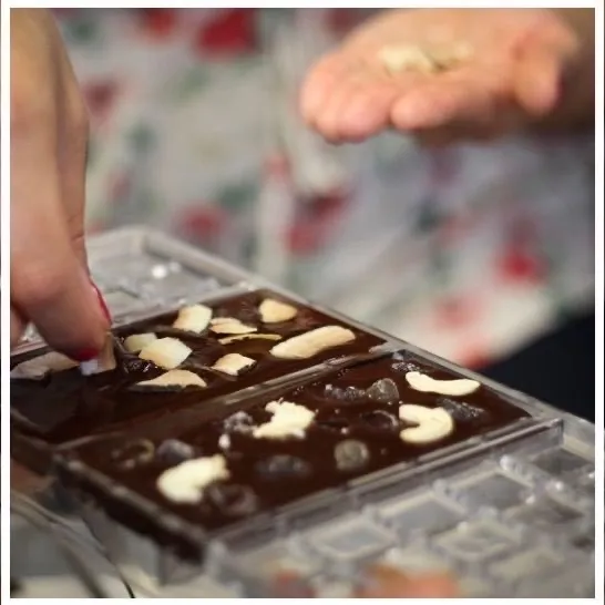 What Makes Handcrafted Chocolate Different from Commercial Chocolate? 4 filling a chocolate mold during a chocolate making workshop